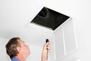 Man looking into an air vent on ceiling